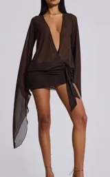 Vestido corto de tul color marrón, con escote profundo en V, mangas largas acampanadas y detalle de nudo lateral en la cintura.