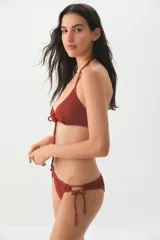Conjunto de bikini color terracota con textura acanalada. El top es de estilo triangular con un detalle de abertura central y cordones ajustables. La bombacha es de corte clásico con tiras laterales para anudar.