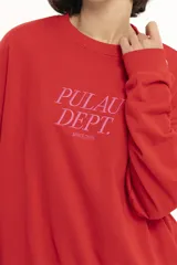 Buzo de algodón rojo con cuello redondo y mangas largas. Estampado frontal con el texto 'Pulau Dept. Since 2023' en color rosa.