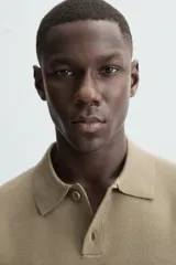 Polo de punto de manga larga con cuello solapa y cierre frontal de botones. Presenta un diseño de corte regular con aberturas laterales en el bajo.