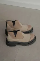 Botas tipo Chelsea de caña corta con diseño bicolor en tonos marrón y negro. Presentan paneles elásticos laterales, puntera reforzada y suela track robusta con plataforma.