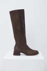 Bota de caña alta color marrón, confeccionada en cuero con textura, con taco cuadrado de altura media y punta redondeada.