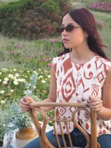 Chaleco de lino estampado con diseño ikat en tonos marrón y crudo, sin mangas, con cuello redondo y cierre frontal de botones tapados.