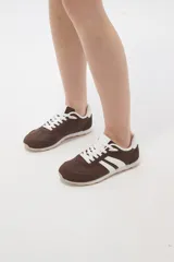 Zapatillas de estilo urbano color marrón con detalles en blanco, confeccionadas en material textil y sintético, con cordones blancos y suela de goma.