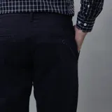 Pantalón de gabardina color azul marino, de corte ajustado y tiro medio, con cierre y botón frontal.