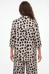 Camisa de manga larga con estampado animal print tipo leopardo, cuello camisero y cierre frontal de botones negros.