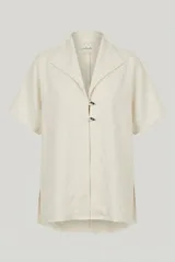 Sobrecamisa de lino color crudo, con cuello solapa, mangas cortas y cierre frontal con dos botones.