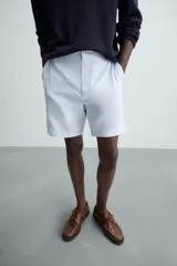 Bermuda azul marino de corte regular fit, confeccionada en tejido de algodón y lino. Cuenta con bolsillos frontales y traseros, cierre frontal con cremallera y botón.