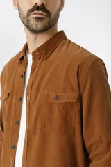 Camisa de pana color azul marino, con mangas largas, cuello clásico y dos bolsillos frontales con solapa y botón.