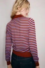 Jersey de punto con diseño a rayas horizontales en color rojo y lila, cuello solapa tipo polo con cierre frontal de botones y manga larga.