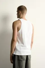 Camiseta sin mangas tipo tank top de corte slim fit, confeccionada en tejido de algodón con elasticidad, cuello redondo amplio y vivos en tejido combinado a tono.