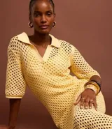 Vestido midi color amarillo pálido con efecto crochet, cuello polo, manga corta y abertura lateral. Confeccionado en algodón BCI más sostenible.