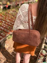 Cartera baguette de cuero color marrón con forro interno de tela.