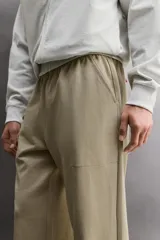 Pantalón jogger de corte relajado confeccionado en tejido compacto de algodón. Presenta cintura elástica con cordón interior, bolsillos frontales en la cadera y un bolsillo trasero de plastrón.