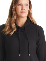 Buzo de tejido suave color gris melange, con cuello volcado ajustable mediante cordones con punteras metálicas. Presenta mangas largas con puños anchos decorados con botones metálicos, hombros caídos y un diseño de silueta holgada con ruedo redondeado y aberturas laterales.