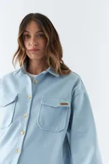 Sobrecamisa color rosa con cuello camisero, cierre frontal con botones, dos bolsillos de parche con solapa en el pecho, mangas largas con puños abotonados y corte holgado.