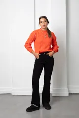 Buzo de lana color coral con diseño de tejido trenzado, cuello redondo y mangas largas.