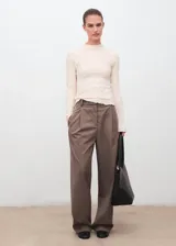 Top de manga larga con cuello alto festoneado y textura arrugada. Presenta un diseño entallado y acabado delicado en los bordes.