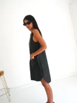 Vestido corto negro sin mangas, con cuello redondo y bolsillos laterales. Presenta un bordado de sol en el pecho.