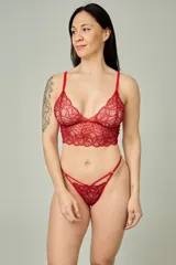 Conjunto de lencería rojo de encaje, compuesto por un corpiño tipo bralette con diseño alargado y tirantes regulables, y una tanga regulable con tiras cruzadas al frente.