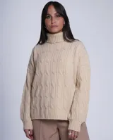 Sweater de punto color beige con cuello alto tipo polerón y diseño de ochos verticales. Presenta mangas largas con puños ajustados y un corte holgado.