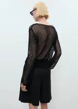 Jersey de punto grueso negro con cuello barco, manga larga y detalles florales bordados en el frente.