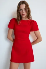 Vestido mono corto de color rojo, con cuello redondo y mangas cortas abullonadas. Cuenta con forro interior tipo shorts combinado a tono y cierre en la espalda con cremallera oculta.