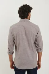 Camisa de manga larga con cuello abotonado, cierre frontal con botones y bolsillo en el pecho. Presenta un diseño de textura melange en tono azul piedra.