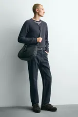 Bandolera negra de cuero sintético con correa ajustable para el hombro y cierre con solapa con hebilla decorativa.