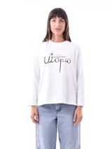 Remera blanca de manga larga con estampado frontal que dice "There's no place like Utopio" en negro.