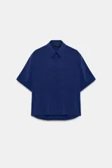 Camisa de cuello solapa y manga corta con dobladillo, presenta bolsillos de plastrón en el frente, bajo asimétrico y cierre frontal con botones ocultos.