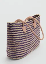 Bolso tipo shopper de diseño trenzado en fibras naturales de hoja de palma de coco, con combinación de colores violeta y natural. Cuenta con doble asa de hombro trenzada en cuero color beige y detalles de sujeción en cuero.