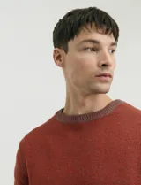 Sweater de punto con cuello redondo, manga larga y puños y ruedo acanalados. Presenta un diseño jaspeado en tonos oscuros.