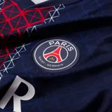 Camiseta de fútbol Nike del Paris Saint-Germain, modelo local. Diseño azul marino con una franja central vertical roja y blanca con patrón geométrico, escudo del club, logo de Nike y sponsor Qatar Airways.