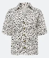 Camisa de manga corta en tejido de viscolino con estampado de lunares irregulares, cuello camisero en pico y abotonado frontal.