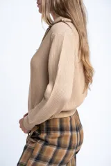 Campera tejida de algodón con cierre frontal completo y cuello alto. Presenta una textura acanalada vertical y puños y ruedo elásticos.