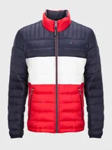 Chaqueta acolchada Tommy Hilfiger con diseño a bloques de color azul marino, blanco y rojo. Tiene cuello alto, cierre de cremallera, dos bolsillos delanteros con cremallera y logo bordado en el pecho.