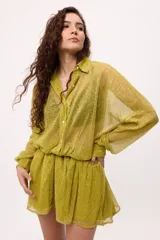 Vestido corto de chiffon color verde lima, con transparencia, cuello camisero, botones frontales y elástico en la cintura. Las mangas son largas y abullonadas con puños elásticos.