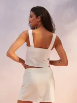 Musculosa corta de color blanco, confeccionada con mezcla de lino, con escote cuadrado y tirantes anchos.