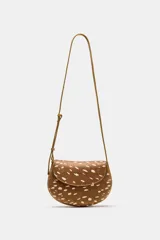 Bolso bandolera de diseño estructurado, con cuerpo en estampado animal tipo cervatillo en tonos marrón y blanco. Cuenta con solapa curva, cierre de botón imantado, bolsillo interior con cremallera y correa larga ajustable.