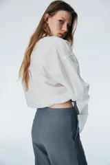 Pantalón sastrero gris de tiro alto, con pliegues marcados al frente y piernas anchas y rectas.