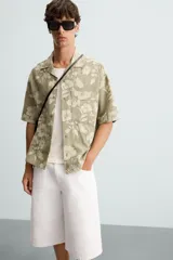 Camisa de manga corta y corte relajado confeccionada en tejido de algodón con diseño jacquard floral. Presenta cuello bowling, un bolsillo de plastrón en el pecho y cierre frontal con botones.