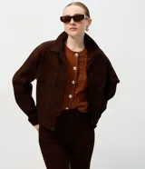 Campera de sarga acanalada color marrón, con cuello camisero estructurado, cierre frontal con botones, mangas largas con puños y bolsillos delanteros con solapa.