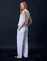 Pantalón de lino de corte recto y tiro medio, con pretina elástica ancha y lazo de ajuste frontal. Presenta bolsillos laterales verticales y bolsillos traseros.