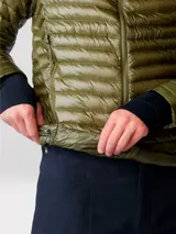 Campera puffer ultraligera de Mountain Hardwear, modelo Ghost Whisperer, color verde oliva. Confeccionada en tejido ripstop reciclado con aislamiento de plumón de 800 cuin con certificación RDS. Presenta cierre frontal completo, cuello alto, dos bolsillos laterales con cierre y puños con ribete elástico.