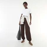 Pantalón marrón de punto arrugado, de corte amplio y holgado con textura, con puños ajustados en los tobillos y tiro alto.