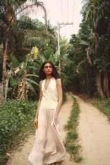 Chaleco color crema de punto, con escote en pico y sin mangas. Cierre cruzado frontal con lazada lateral.