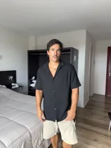 Camisa negra de manga corta, con cuello tipo solapa y textura de punto.