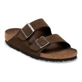 Sandalias Birkenstock modelo Arizona de dos correas ajustables con hebillas metálicas. Presentan una capellada de gamuza marrón, plantilla anatómica de corcho y suela de goma antideslizante.