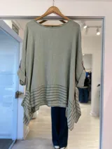 Blusa verde claro con diseño asimétrico, cuello redondo y mangas tres cuartos con detalles de rayas horizontales en el dobladillo inferior y los laterales.